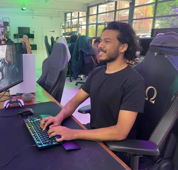 A man from the Video Gamer Team sitting in front of a computer playing a game.