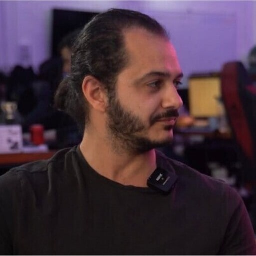 A man in a black shirt is sitting in front of a computer, engrossed in a video game.