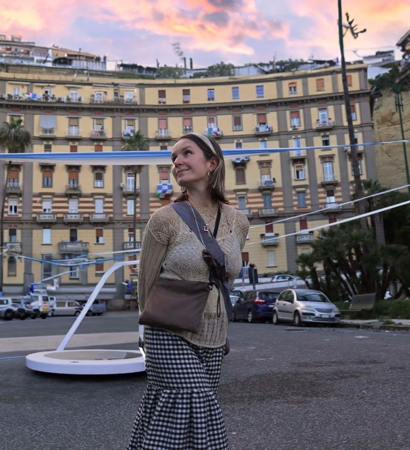 Rosa Fryer is standing in front of a building. at sunset while being cheered on by her video gamer team.