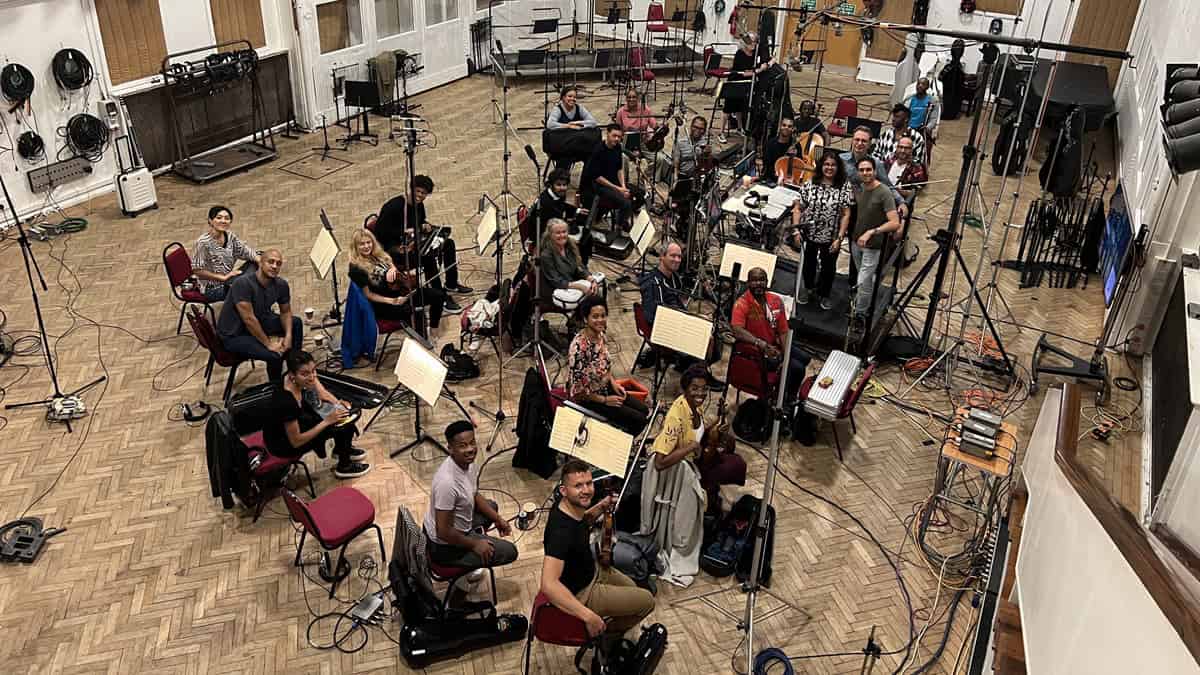 Musicians sit together with instruments for a string session to create a game's soundtrack.