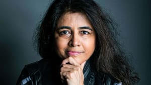 A person with long dark hair poses in front of a camera.