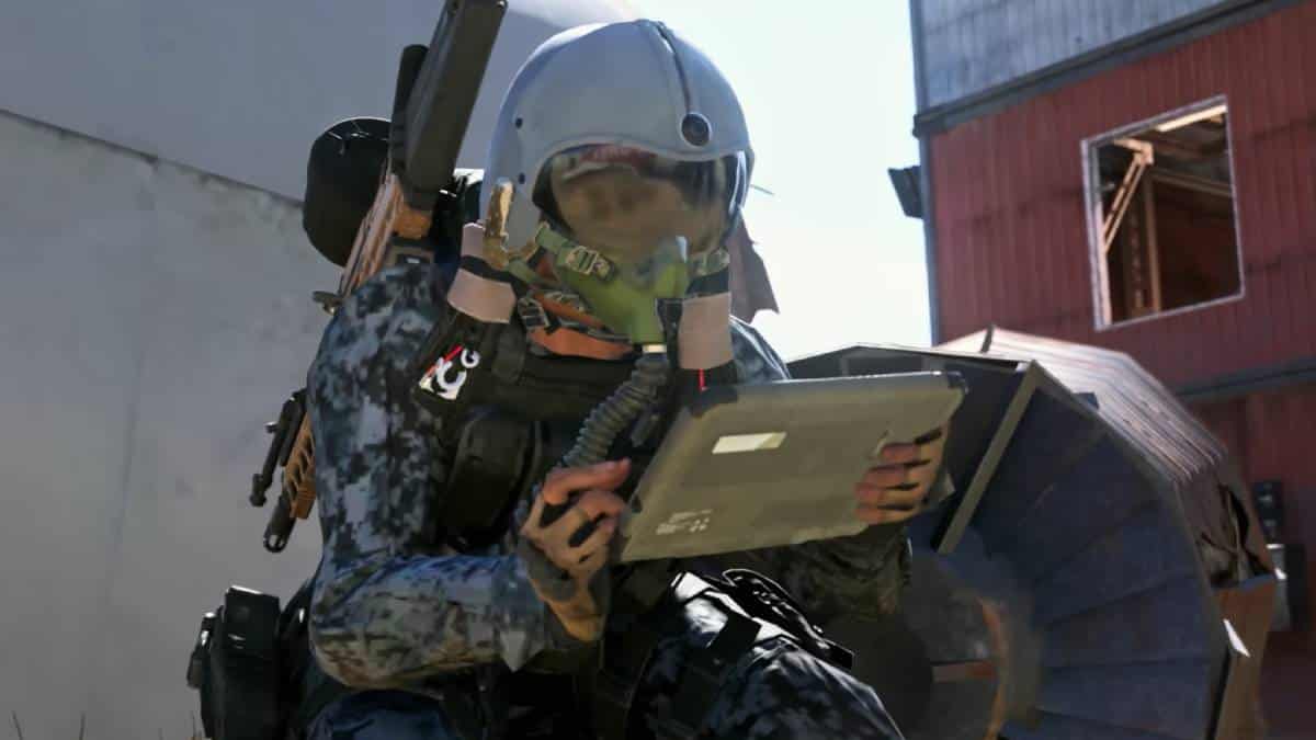 Soldier in camouflage and helmet reviewing the best settings for Warzone Mobile - graphics and audio on a tablet outdoors.
